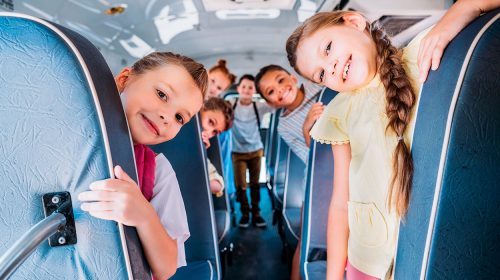 group of cute schoolchildren riding on school bus and looking at camera