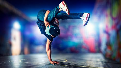 Young man break dancing at night on urban painted walls background